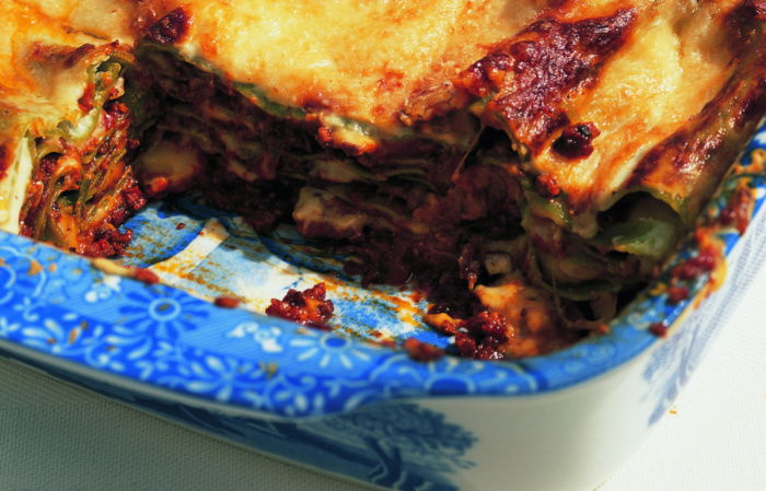 picture of a blue and white willow pattern dish containing cooked lasagne with a portion removed