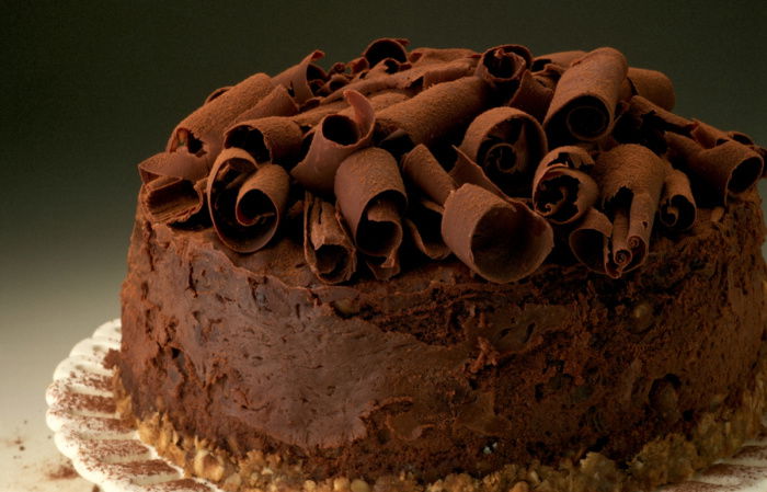 a picture of chocolate cheesecake on a white plate, with chocolate curls on the top