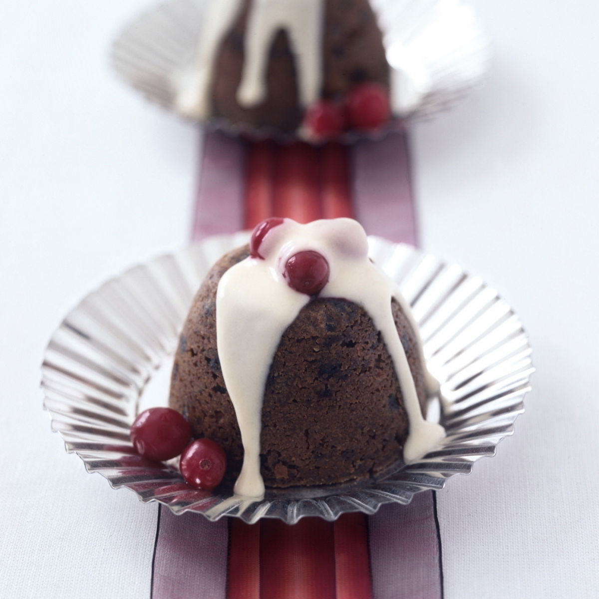 two pretty individual mini christmas puddings on silver plates