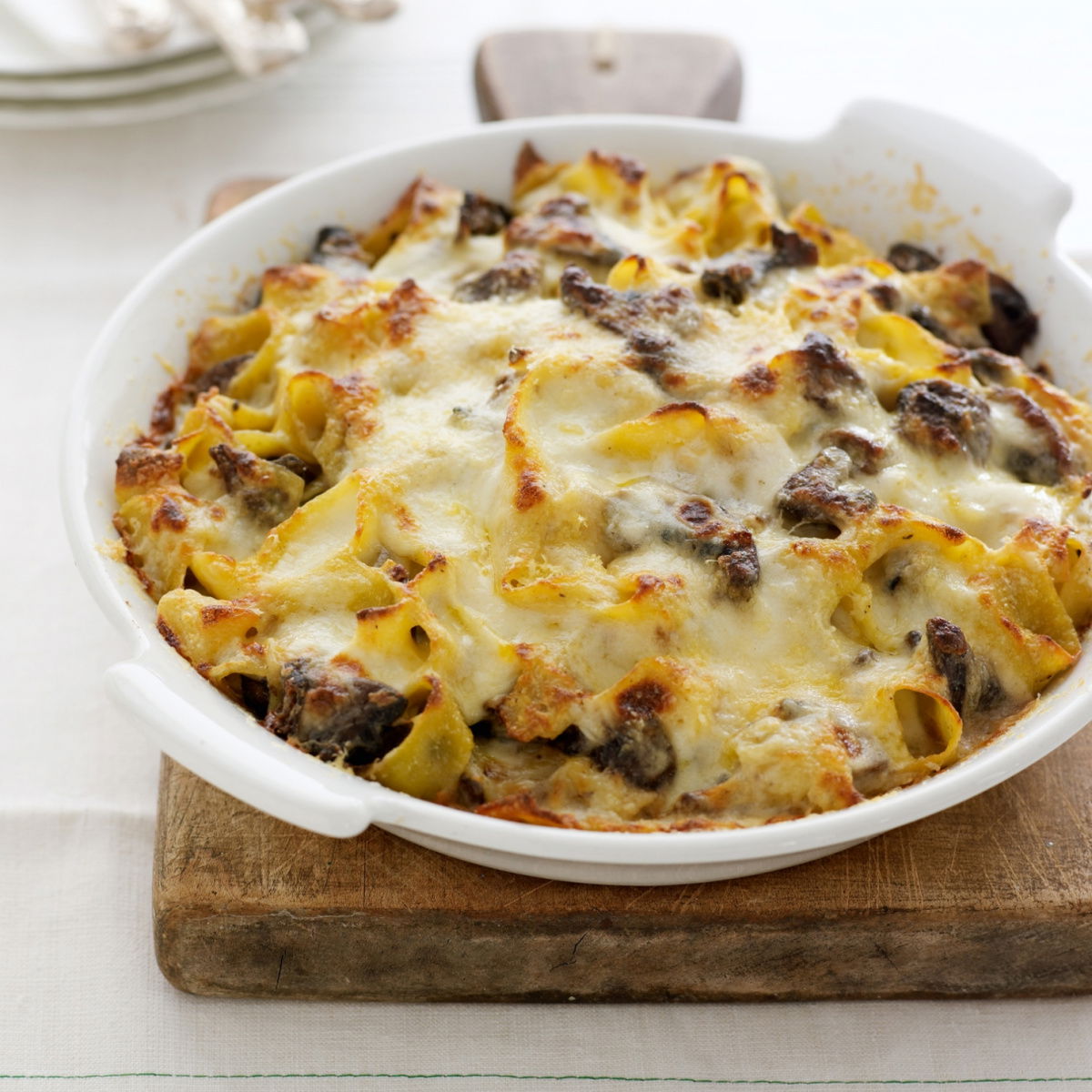 A white oven proof dish of a baked pasta dish with melted cheese on the top