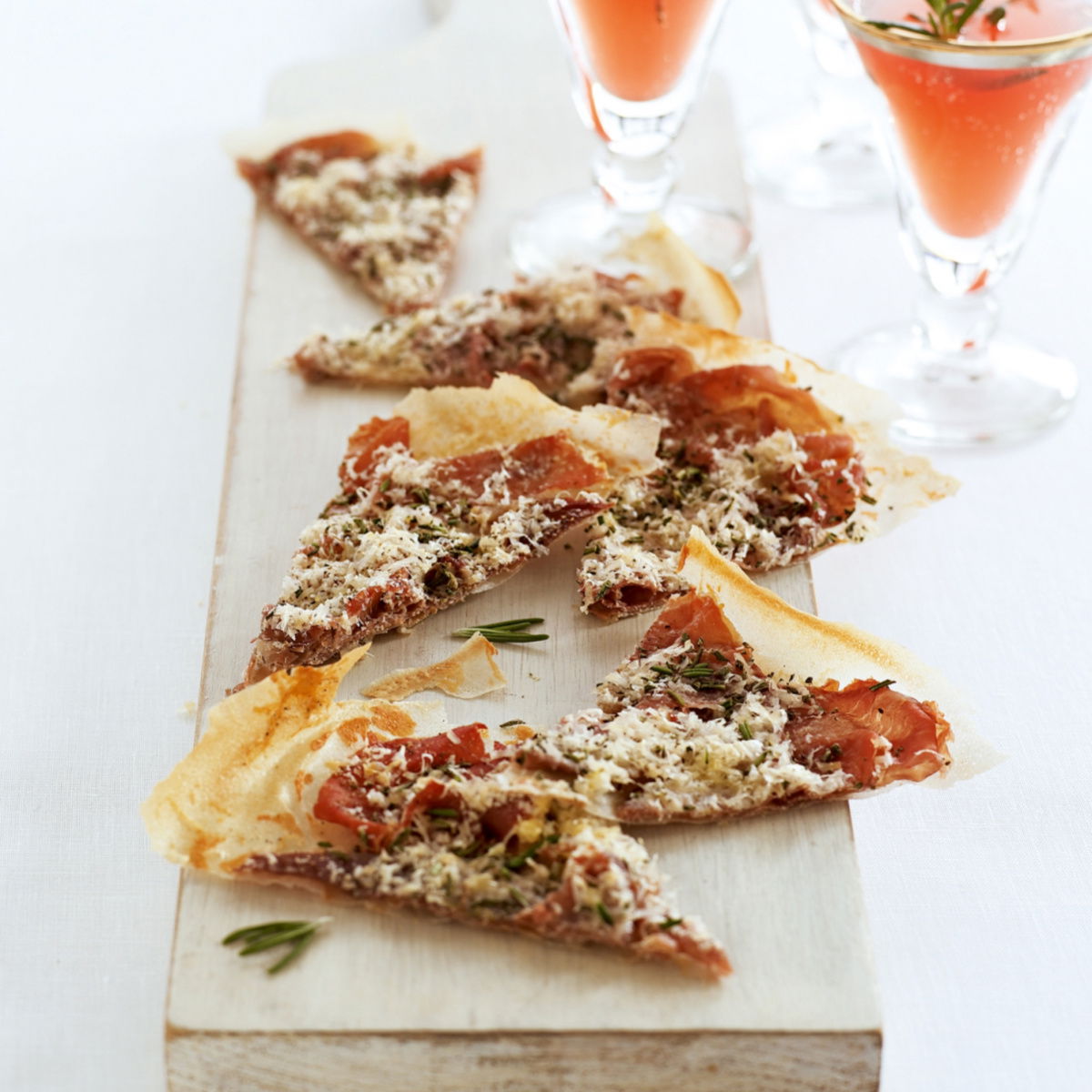 bite-sized parma ham pecorino and rosemary crisps on a wooden board with drinks