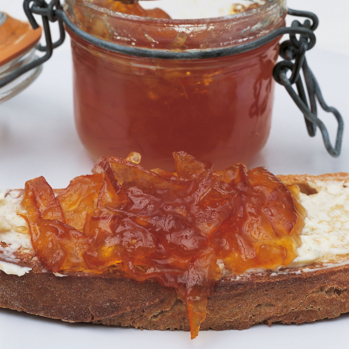 A picture of seville orange marmakad in a kilner jar with a slice of buttered toast in front with a dollop of marmalade on top