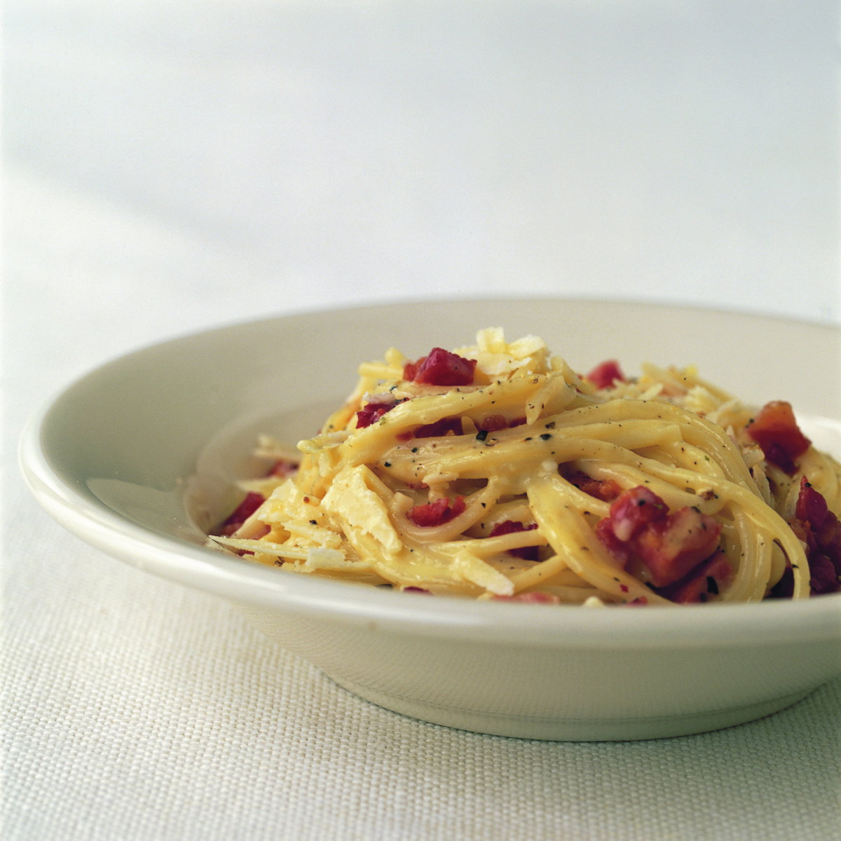 a picture of a white bowl with cooked spaghetti carbonara