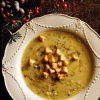 A picture of a cream bowl with soup and croutons and some winter berries on the table