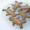 Five little gingerbread men lying on a circular wire tray four of them with the names Tom, Sophie, Max and Charlotte iced on their tummies