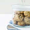 A lidded glass jar full of rock cakes on a folded blue and white napkin