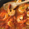 Close-up of a dish featuring prawns in a rich, tomato sauce giving a vibrant and appetising appearance.