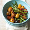 A picture of cooked pork stew with green beans and potatoes in a blue bowl