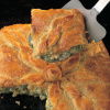 a flaky fish pie with a slice taken out showing the filling and the crumbly pastry.