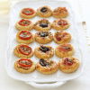 a picture of a white plate full of little puff pastry tarts with assorted toppings