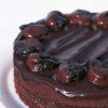 a picture of a round chocolate sponge cake on a white plate with chocolate covered prunes decorating the top