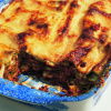 picture of a blue and white willow pattern dish containing cooked lasagne with a portion removed