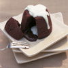 a picture of a chocolate sponge pudding on a white plate with a slice take out showing the melted chocolate inside