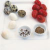 a picture of a white plate with quails eggs, tomatoes and two white dishes of salt