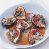 a picture of halved figs in a white dish with honey and gorgonzola drizzled on top