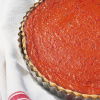 a picture of a red pepper and tomato tart in a fluted tin on a red and white tea towel
