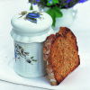 a slice of toast propped up next to a pretty china jar with blue flowers drawn on the side and a white vase with blue flowers behind it