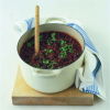 a white casserole dish containing ragu bolognaise sauce with basil sprinkled on top, and a blue and white tea towel