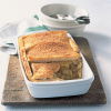 An oblong white dish with apple and orange filling and a layer of thin slices of bread to make the crunch topping