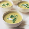 Four white bolws of leek and potatoe soup with creme fraiche swirled on top and a garnish of snipped chives