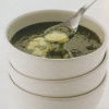 a picture of spinach soup and melted cheese in a white soup bowl with spoon