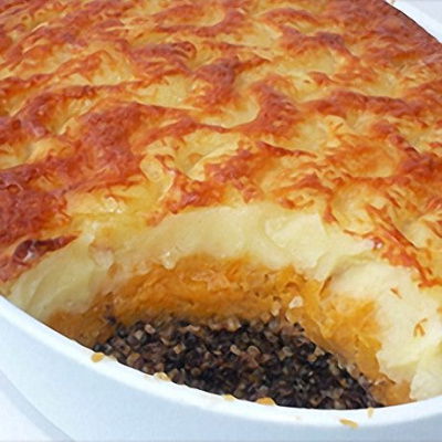 haggis pie in a white dish with a portion removed showing the filling of haggis, swede and potato