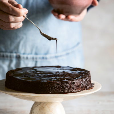a picture of a chocolate and almond cake on a marble cake stand 