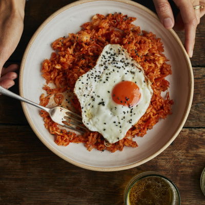 a picture of a bowl of kimchi fried rice sitting on a wooden table top