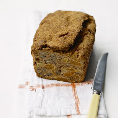 A picture of a cooked loaf cake on a red and white folded teatowel with a knife next to it