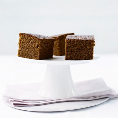 three slices of gingerbread cake on a white pedestal cake stand
