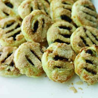 A picture of a batch of cooked eccles cakes, all lined up overlapping each other