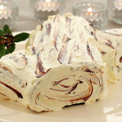 a picture of a Chocolate Chestnut Log made of white chocolate log on a cream plate with glass tea lights in the background