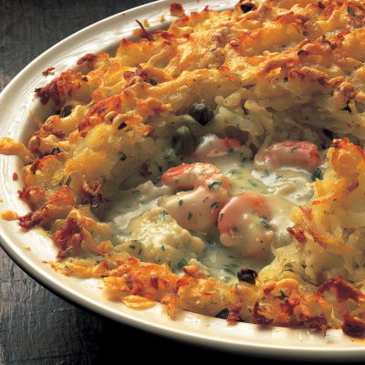 picture of a white dish containing prawns and other fish pie with a potato topping