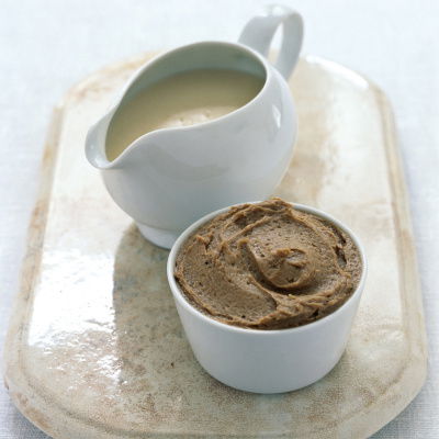 a white jug of cumberland rum sauce and a bowl of brandy butter on a marble serving board