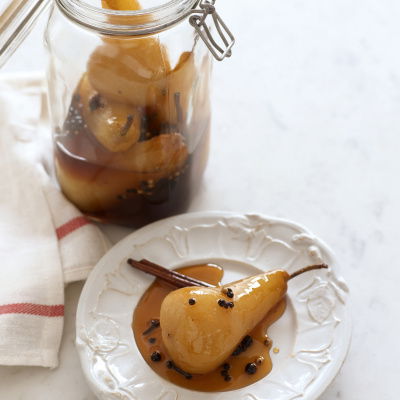 pickled pears in a glass kilner jar with a single pear on a white plate