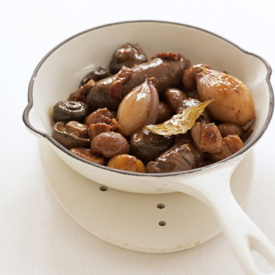 a picture of venison sausages braised in white wine in a white pan