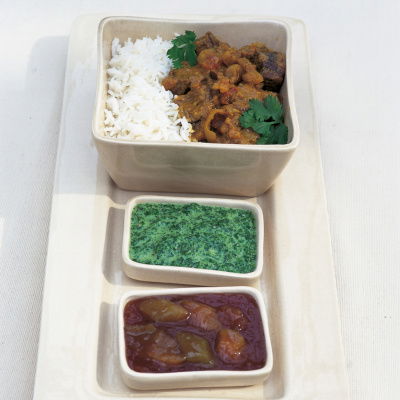 three white dishes containing beef curry rice and coriander
