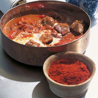 Braised beef goulash in a copper tin with a little bowl of smoked pimenton next to it and a little blue and white jug