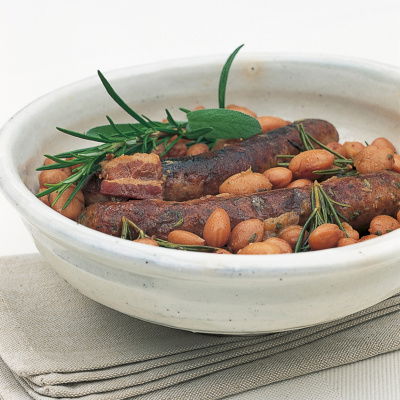 a picture of cooked sausages and borlotti beans in a white bowl on a folded napkin