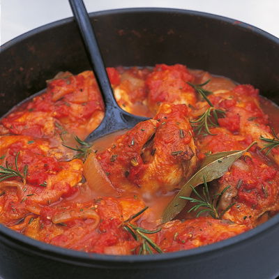 a pan of cooked chicken cacciatora with chicken thighs, rosemary and a tomatoey sauce