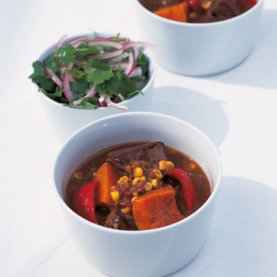 A picutre of three white bowls, two containing the beef stew and one with a side salad