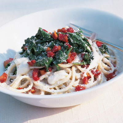 a white bowl of linguine with a gorgonzola sauce, cubes of mozarella, spinach, bacon and parmesan on top 