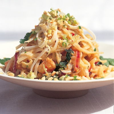 a close up of a plate of pad thai noodles pile up 