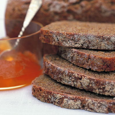 three slices of wholemeal bread next to a glass jar of marmalade