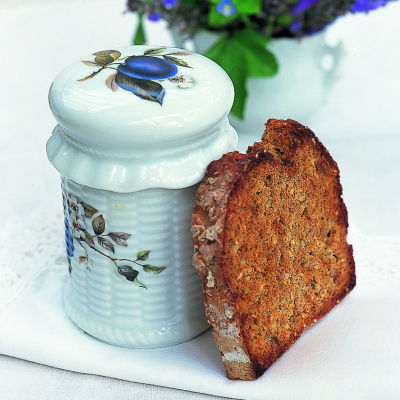 a slice of toast propped up next to a pretty china jar with blue flowers drawn on the side and a white vase with blue flowers behind it