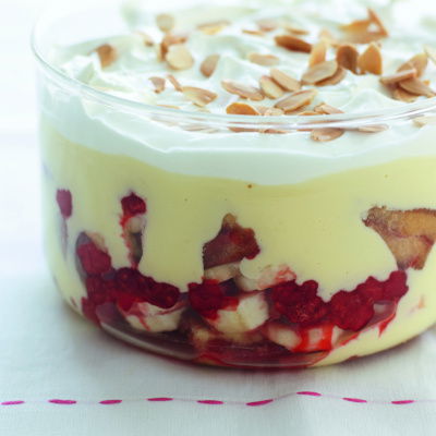 A picture of a glass bowl layered with sponge, fruit custard and cream making a trifle