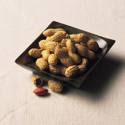 A picture of a black square dish containing peanuts in their shells