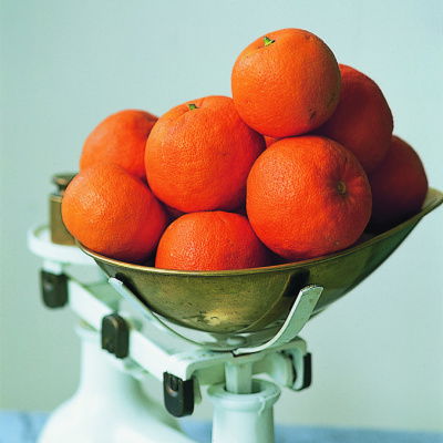 A picture of a set of white weighing scales full of oranges