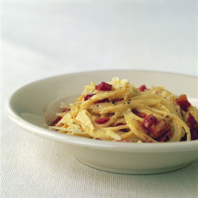 a picture of a white bowl with cooked spaghetti carbonara