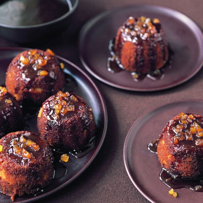 three plates of little sticky gingerbread puddings with wine and brandy sauce poured over